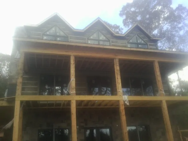 Dormers and porch framing on a large log home under construction — Roof Coating work by our crew in Canterbury